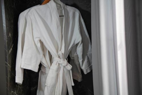 a white robe is hanging on a door at Madelise Ensora Hotel & Travel in Hanoi