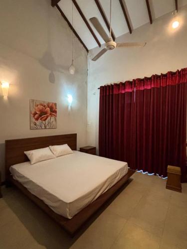 a bedroom with a bed and a red curtain at Nymph Villa in Pannipitiya