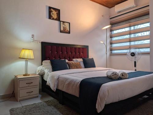 a bedroom with a large bed with a red headboard at Baobab Lodge Douala - Makepe in Douala