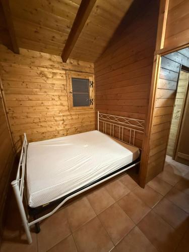 an empty bed in a wooden room with a window at Campeggio Il Delfino in Rocca Imperiale