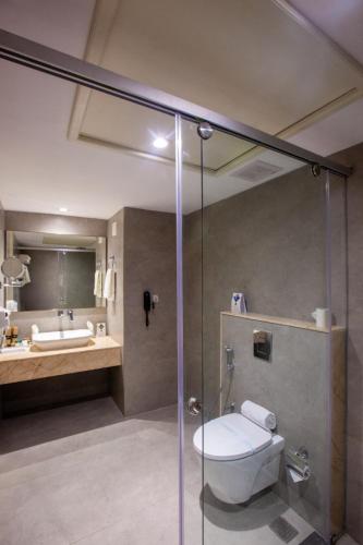 a bathroom with a shower with a toilet and a sink at Holiday Hotel in Cherai Beach