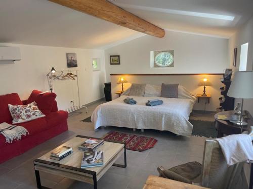 a living room with a bed and a red couch at Le cabanon de la bergerie in Grignan