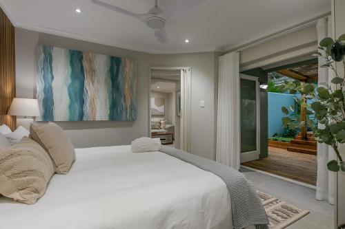 a bedroom with a large white bed and a balcony at Lagoon Point Lodge in Knysna