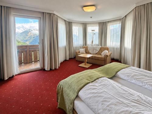 a bedroom with a bed and a couch and a window at Alpinresort Schillerkopf in Bürserberg