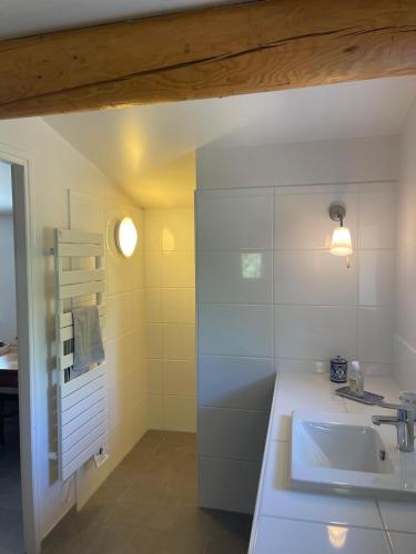 a white bathroom with a sink and a mirror at Le cabanon de la bergerie in Grignan