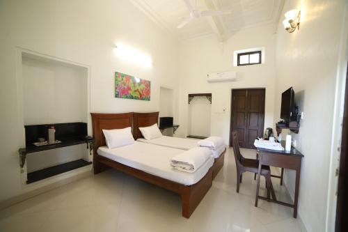 a bedroom with a bed and a desk and a television at Lodha Heritage in Ajmer