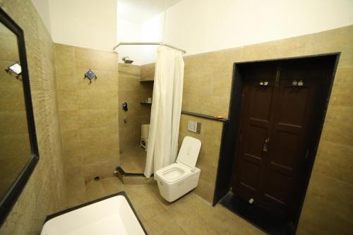a bathroom with a toilet and a brown door at Lodha Heritage in Ajmer