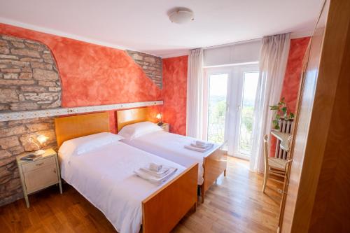 a bedroom with two beds and a stone wall at Albergo Osteria Leso1815 in Bosco Chiesanuova