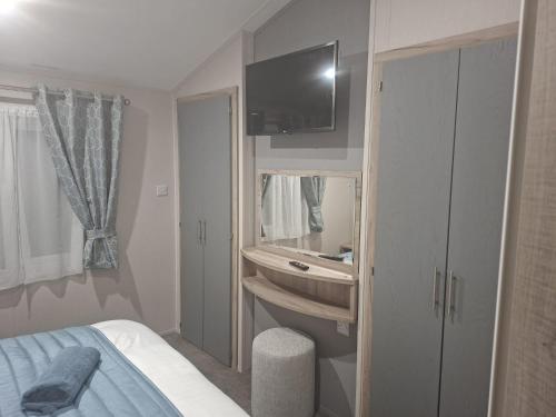 a bedroom with a bed and a sink and a tv at Crescent Lodge in Forton
