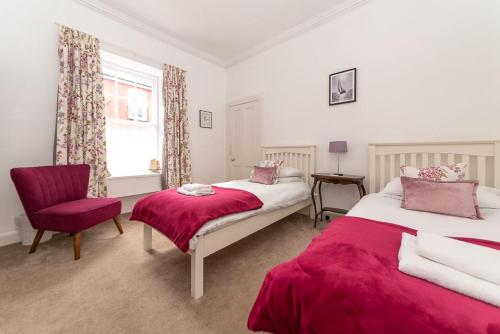 a bedroom with two beds and a chair and a window at Beresford Cottage in North Berwick