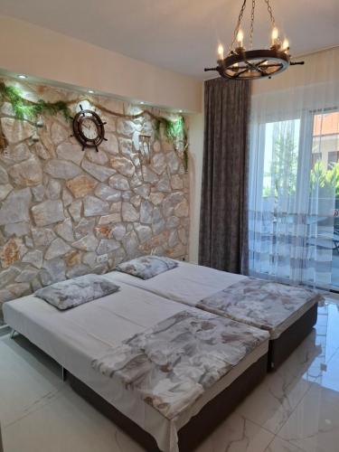 a bedroom with two beds in front of a stone wall at Апартаменты in Hanioti