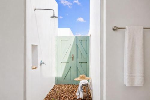 a woman sitting in a chair in front of a green door at The Cottage Collection Paternoster in Paternoster