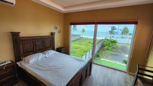 a bedroom with a bed and a large window at Villa Patty by the beach in El Conacaste