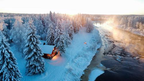 a truck driving down a river with snow covered trees at Lapland Aurora Riverside in Raiskio