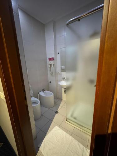 a bathroom with a toilet and a glass shower at BAR RESTORANT HOTEL ALPET Elbasan in Elbasan
