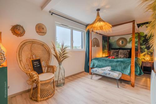 a bedroom with a canopy bed and a chair at Lodge de la Jungle avec Spa in Nanteuil-lès-Meaux