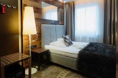 a bedroom with a bed and a lamp and a window at Sandra Spa Karpacz & Aquapark in Karpacz