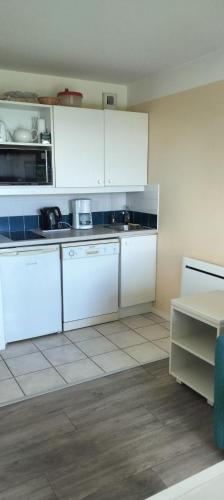 a white kitchen with white cabinets and a table at Studio face à l océan in Les Sables-d'Olonne