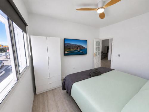 a white bedroom with a bed and a ceiling fan at Noalys Entre Mar y Valle in Agaete