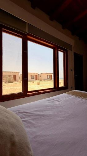 a bedroom with a bed and windows with a view of a desert at Matarma Bay Hotel in Ras Sedr
