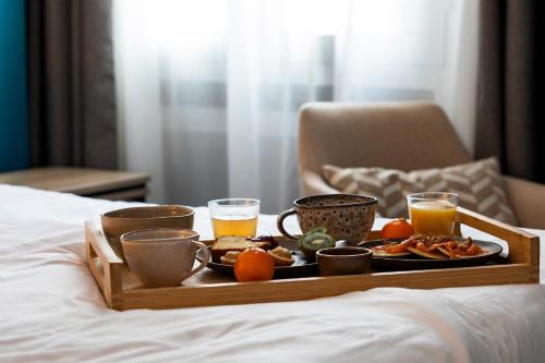 a tray of breakfast food on a bed with glasses of orange juice at Oceania Hôtel d'Anjou Angers in Angers