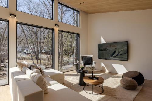 a living room with white furniture and large windows at Kuro Hakuba in Hakuba