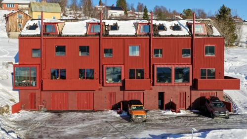 a red building with cars parked in the snow at Morgondoppet - Olen Funäsdalen in Funäsdalen