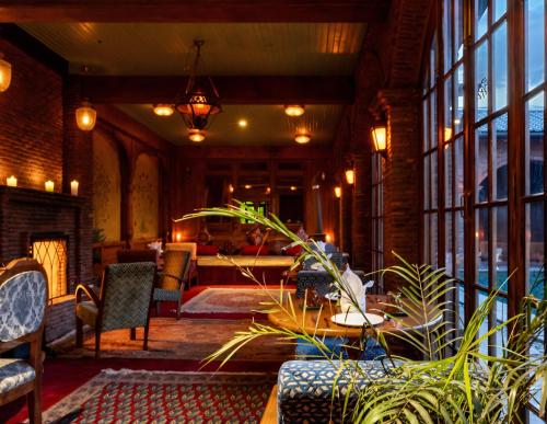 a lobby with a table and chairs and windows at Hazaar Dastaan Kashmir in Srinagar
