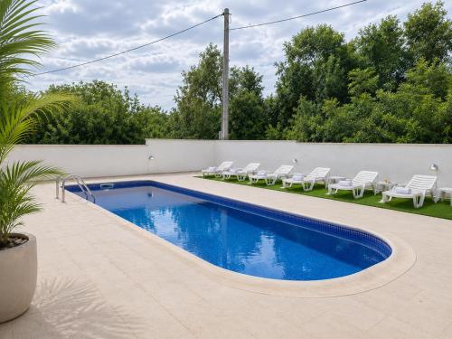 a swimming pool with white chairs next to a fence at Krimovica Sunset Spacious Apartment with Sea View and Pool in Krimovice