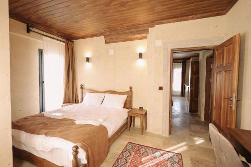 a bedroom with a large bed with a wooden ceiling at Castle Stone House in Uçhisar