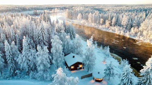 a cabin in the snow next to a river at Villa Jokiranta Northern light Riverside in Ranua