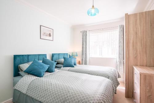 a bedroom with two beds with blue pillows at Boyd’s Bungalow, Lowestoft in Lowestoft