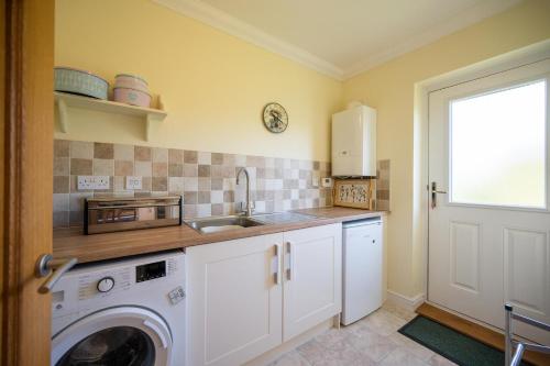 a kitchen with a washing machine and a sink at Boyd’s Bungalow, Lowestoft in Lowestoft