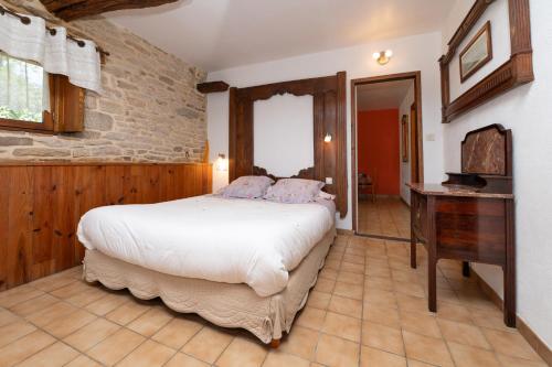 a bedroom with a large bed and a wooden desk at Gîte Peigne De Vénus in Elven