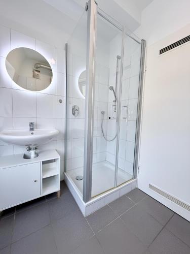 a white bathroom with a shower and a sink at Über den Dächern von Borghorst - direktes Zentrum in Steinfurt