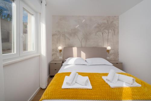 a bedroom with a large bed with two white towels at Lejla Garden Apartment in Podstrana