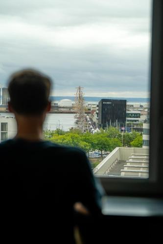 a man looking out of a window at a city at Nomad Hotel le Havre Centre Gare in Le Havre