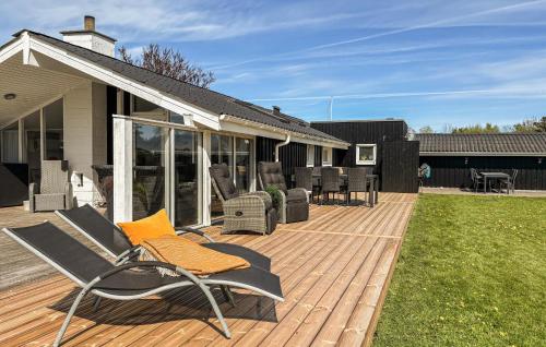 a deck with chairs and tables on a house at 3 Bedroom Awesome Home In Frederikshavn in Frederikshavn