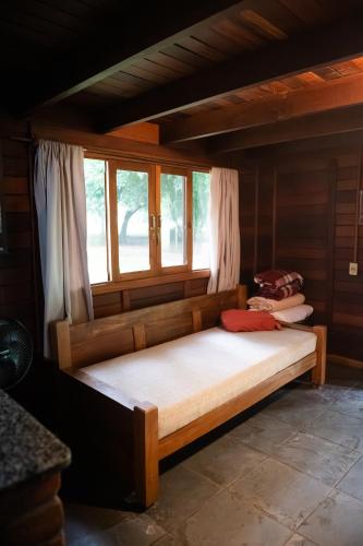 a wooden bed in a room with a window at Pousada Corujas in Cajuru do Sul