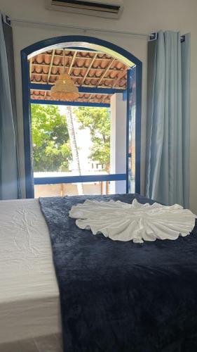 a bed in a room with a large window at Santorini Suítes in Tamandaré