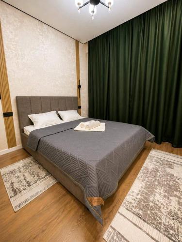 a bedroom with a large bed with a green curtain at Olympic Park Apartments near Almaty Arena in Almaty