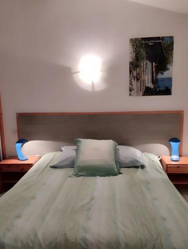 a bed in a bedroom with a light on the wall at Appartement 4p Sanguinet-Doum Doum in Sanguinet