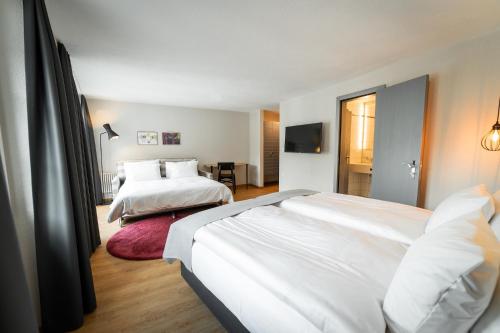 a hotel room with two beds and a television at Boutique Hotel Stockalperhof in Brig