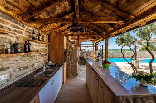 an outdoor kitchen with a stone wall and wooden ceilings at My Dalmatia - Hilltop Paradise with private pool, sauna and Jacuzzi in Kula Atlagić