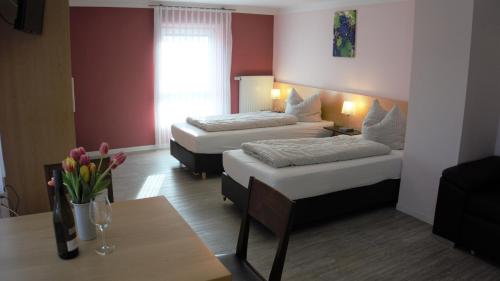 a hotel room with two beds and a table with flowers at Wein- Appartements Borth in Bretzfeld