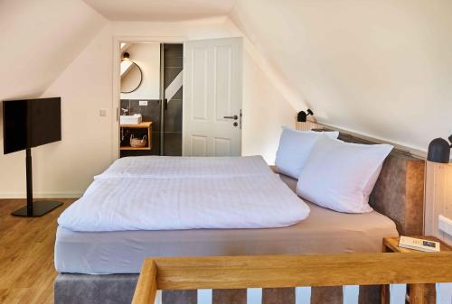 a bedroom with a large bed with white sheets at Reethaus M - Sommerhaus 54 in Grödersby