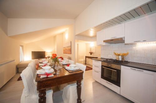 cocina con mesa de madera, armarios blancos y encimera en La Casa Di Luigi, en Gratacasolo
