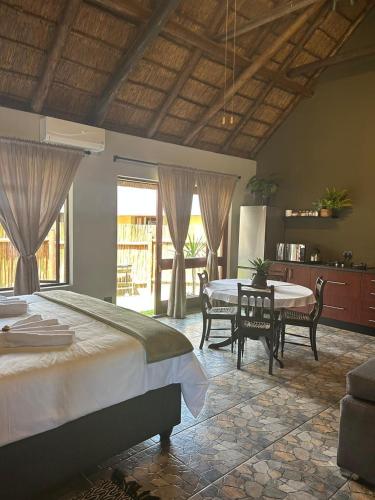 a bedroom with a large bed and a table and chairs at Koro Lodge in Modimolle