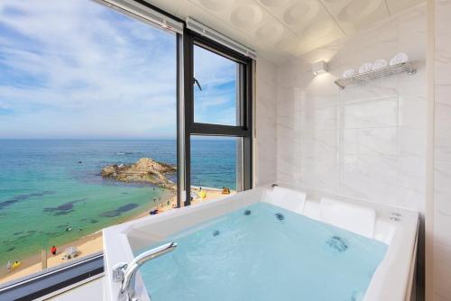 a bathroom with a tub with a view of the ocean at Gangneung Dolgorae Spa Pension in Gangneung