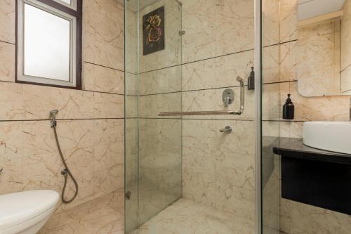 a bathroom with a glass shower with a toilet and a sink at Country Inn Smart Stays, Patna in Patna